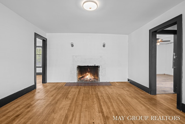 1951 Leonard St NW, Grand Rapids, MI 49504 - unfurnished living room featuring a warm lit fireplace, wood finished floors, and baseboards