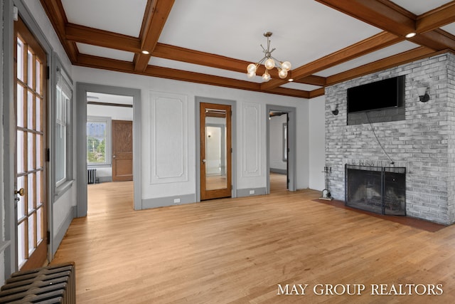 1951 Leonard St NW, Grand Rapids, MI 49504 - unfurnished living room with coffered ceiling, light wood-style floors, beamed ceiling, a chandelier, and a fireplace