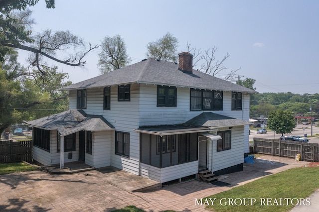 1951 Leonard St NW, Grand Rapids, MI 49504 - back of house featuring a chimney, a sunroom, entry steps, roof with shingles, and a patio area