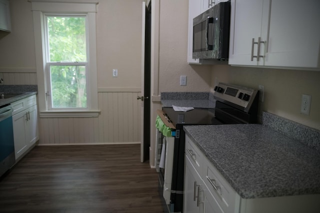 634 Ada St, Kalamazoo, MI 49007 - kitchen with stainless steel electric range oven, black microwave, dark wood finished floors, wainscoting, and white cabinetry