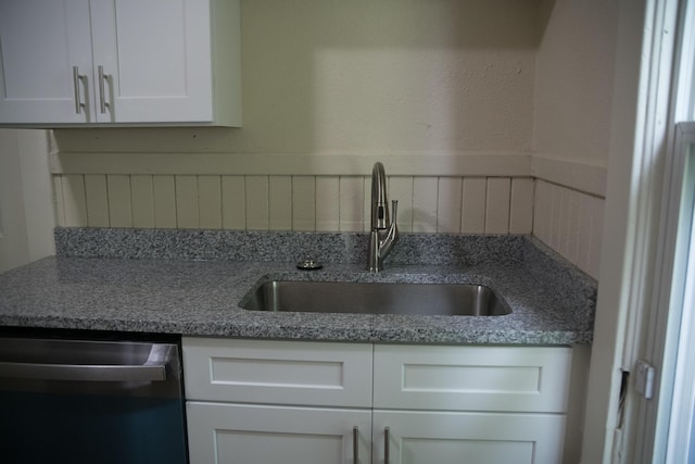 634 Ada St, Kalamazoo, MI 49007 - kitchen with stainless steel dishwasher, a sink, white cabinets, and wainscoting