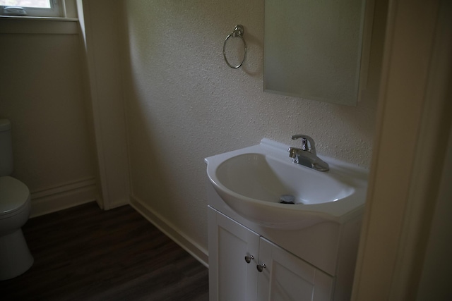 634 Ada St, Kalamazoo, MI 49007 - half bathroom with toilet, vanity, wood finished floors, and a textured wall