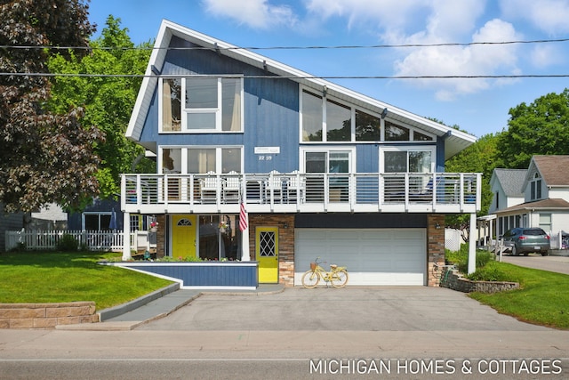 2259 Ottawa Beach Rd, Holland, MI 49424 - view of front of house with driveway, a garage, a balcony, and stone siding