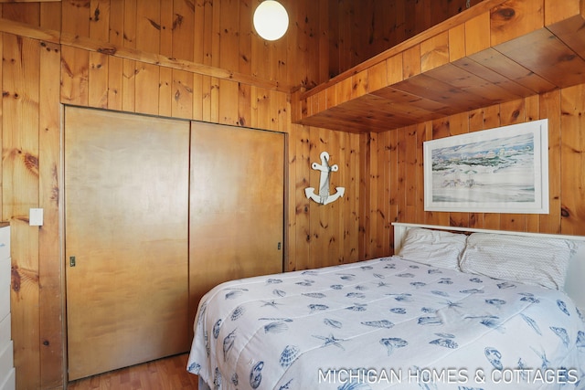 2259 Ottawa Beach Rd, Holland, MI 49424 - bedroom featuring wooden walls, a closet, and wood finished floors