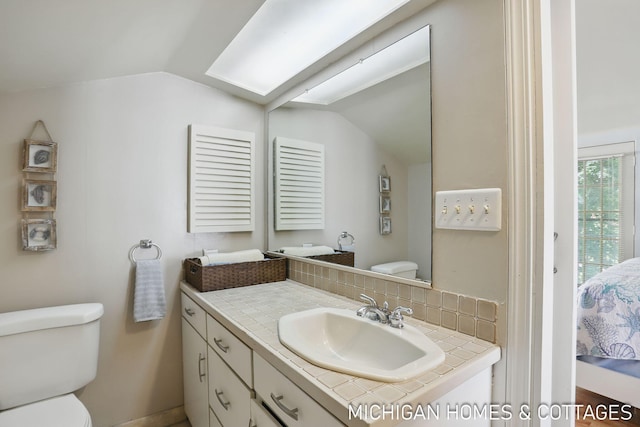 2259 Ottawa Beach Rd, Holland, MI 49424 - bathroom featuring toilet, vaulted ceiling, vanity, ensuite bathroom, and backsplash