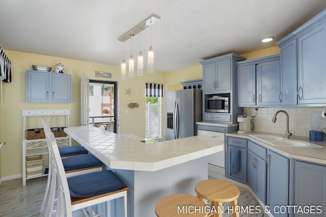 2259 Ottawa Beach Rd, Holland, MI 49424 - kitchen featuring a sink, appliances with stainless steel finishes, tasteful backsplash, light wood-style floors, and a center island