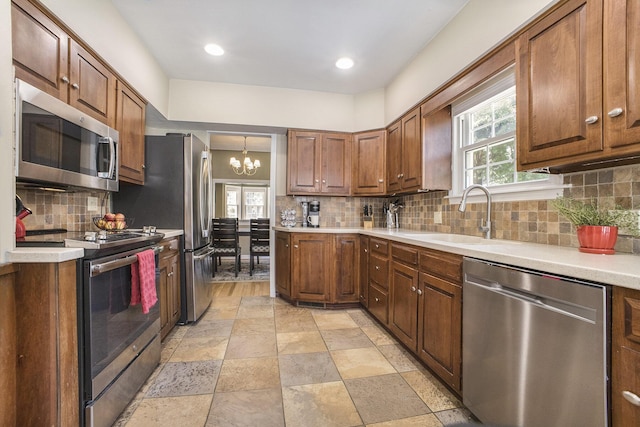 2147 Academy Dr NE, Grand Rapids, MI 49503 - kitchen featuring stainless steel appliances, a sink, a chandelier, light countertops, and backsplash