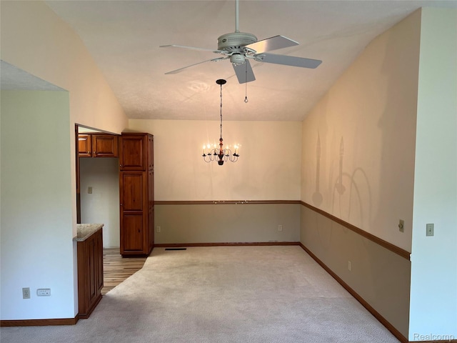 2205 Hammond Place Ctr, Traverse City, MI 49686 - unfurnished dining area featuring light colored carpet, ceiling fan, a chandelier, baseboards, and lofted ceiling