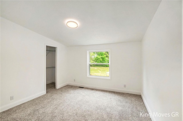 11690 21 Mile Rd NE, Sand Lake, MI 49343 - unfurnished bedroom with carpet floors, baseboards, a spacious closet, and lofted ceiling