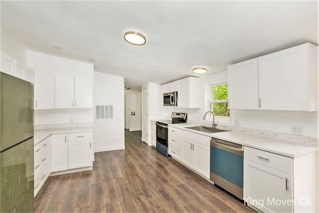 11690 21 Mile Rd NE, Sand Lake, MI 49343 - kitchen featuring appliances with stainless steel finishes, a sink, dark wood-style floors, white cabinetry, and light stone countertops