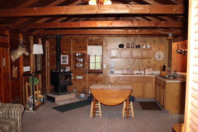 94 E Cherry Creek Rd, Mio, MI 48647 - carpeted dining area featuring a sink, a wood stove, and beamed ceiling