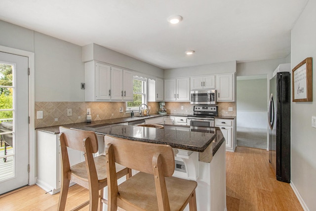 5616 Stoney Brook Rd, Kalamazoo, MI 49009 - kitchen with appliances with stainless steel finishes, light wood-type flooring, a kitchen bar, white cabinets, and recessed lighting