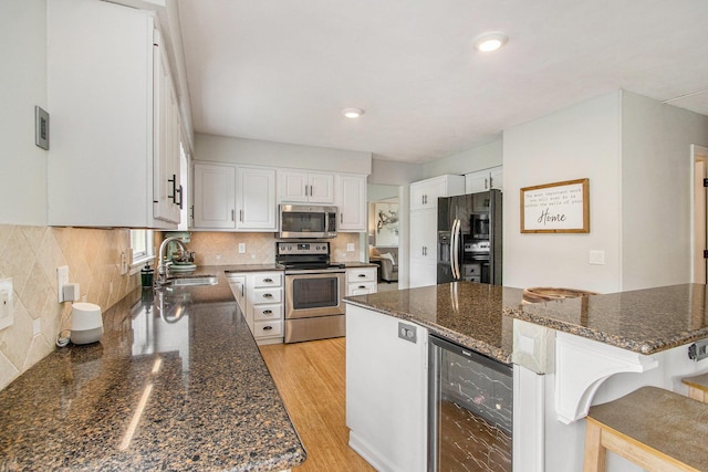 5616 Stoney Brook Rd, Kalamazoo, MI 49009 - kitchen with appliances with stainless steel finishes, beverage cooler, a sink, white cabinets, and a breakfast bar area