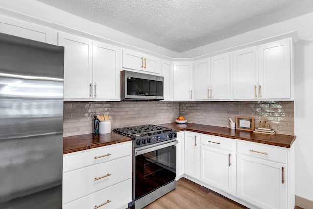 925 133rd Ave, Wayland, MI 49348 - kitchen with stainless steel appliances, wood counters, light wood-style floors, a textured ceiling, and white cabinetry