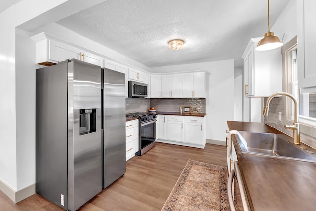 925 133rd Ave, Wayland, MI 49348 - kitchen featuring appliances with stainless steel finishes, a sink, a textured ceiling, light wood-style floors, and white cabinetry