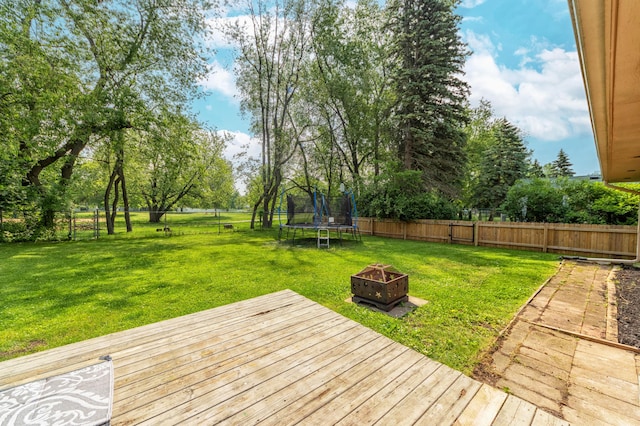 1110 Piccadilly Rd, Kalamazoo, MI 49006 - wooden terrace featuring a trampoline, an outdoor fire pit, and view of wooded area