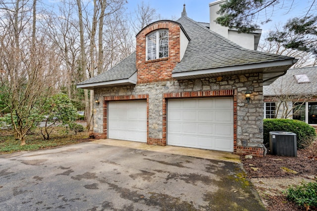 6242 131st Ave, Saugatuck, MI 49453 - view of home's exterior featuring roof with shingles, a chimney, central AC unit, and stone siding