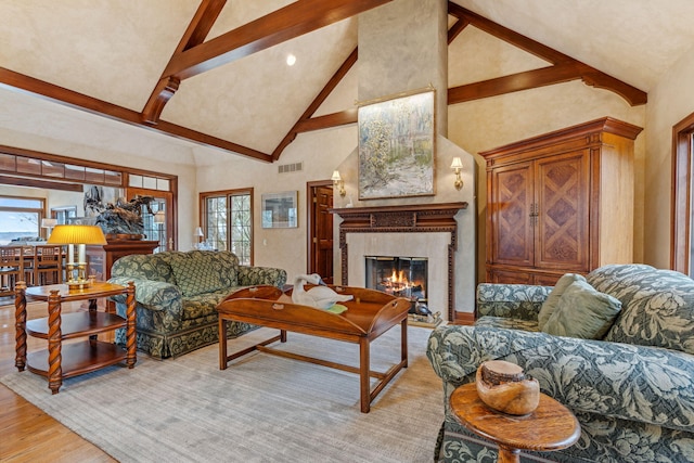 6242 131st Ave, Saugatuck, MI 49453 - living area featuring high vaulted ceiling, plenty of natural light, a tile fireplace, light wood-style floors, and beamed ceiling