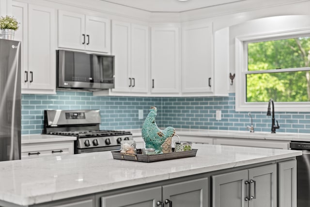 2980 N Old State Rd, Weidman, MI 48893 - kitchen featuring appliances with stainless steel finishes, a sink, gray cabinetry, tasteful backsplash, and light stone countertops