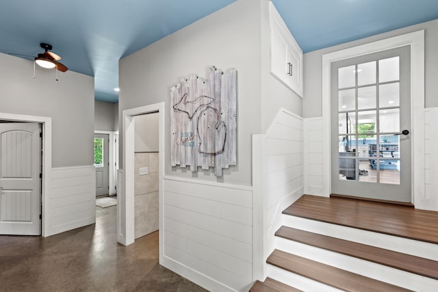 2980 N Old State Rd, Weidman, MI 48893 - stairs with healthy amount of natural light, a ceiling fan, a wainscoted wall, and finished concrete flooring