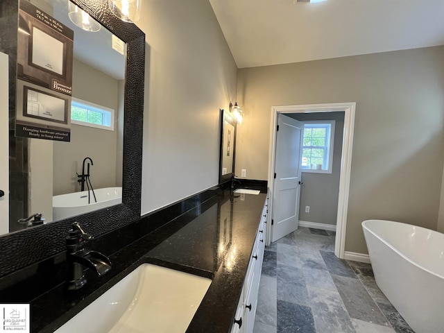3801 Sutton Rd, Metamora, MI 48455 - full bath featuring double vanity, a soaking tub, baseboards, and stone finish flooring