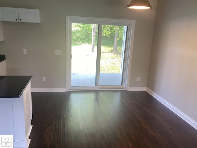 3801 Sutton Rd, Metamora, MI 48455 - unfurnished dining area with dark wood-style flooring and baseboards