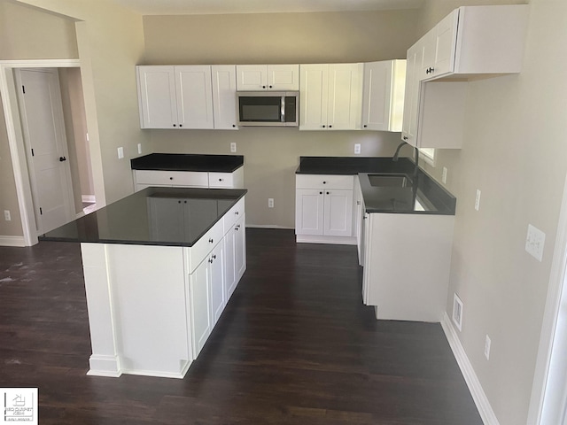 3801 Sutton Rd, Metamora, MI 48455 - kitchen featuring stainless steel microwave, a sink, dark wood-style floors, baseboards, and white cabinets