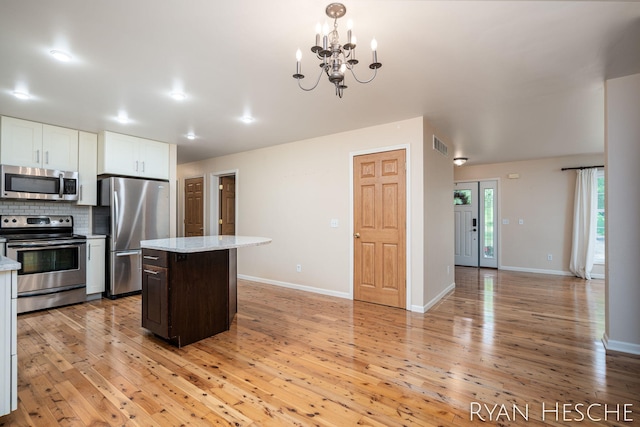 5181 Scotch Mist Dr, Saranac, MI 48881 - kitchen featuring appliances with stainless steel finishes, light wood finished floors, tasteful backsplash, and white cabinetry