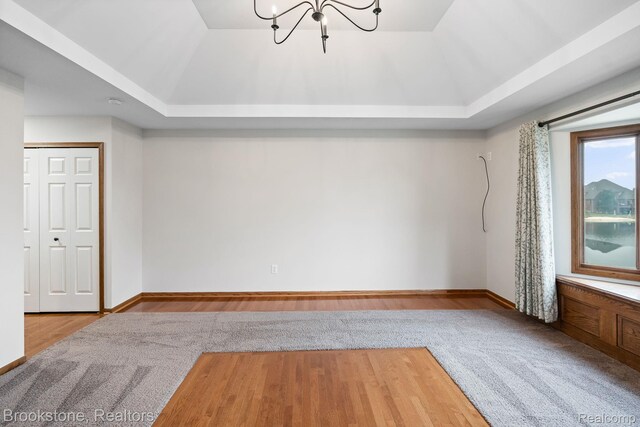 26569 Autumn Lake Dr, Chesterfield, MI 48051 - unfurnished room with a raised ceiling, a chandelier, wood finished floors, and baseboards