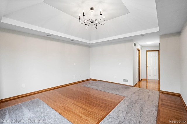 26569 Autumn Lake Dr, Chesterfield, MI 48051 - empty room featuring a raised ceiling, a chandelier, wood finished floors, and baseboards