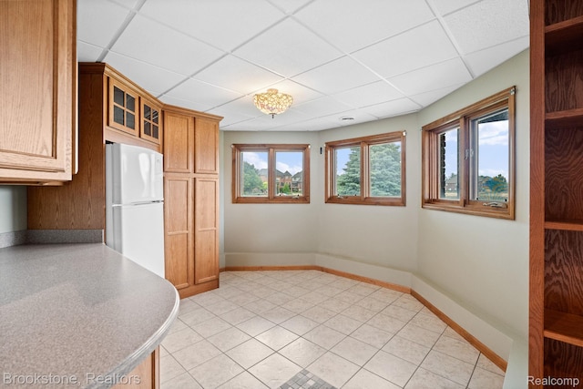 26569 Autumn Lake Dr, Chesterfield, MI 48051 - kitchen featuring freestanding refrigerator, a drop ceiling, baseboards, brown cabinetry, and glass insert cabinets