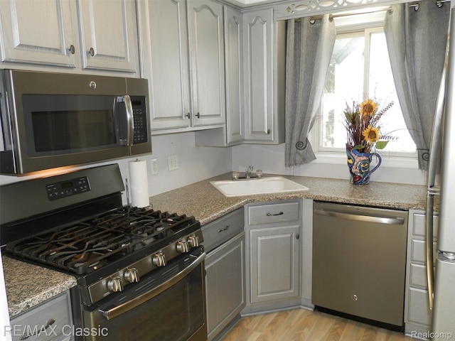 25207 Fortuna St, Roseville, MI 48066 - kitchen featuring appliances with stainless steel finishes, a sink, gray cabinetry, and light wood-type flooring