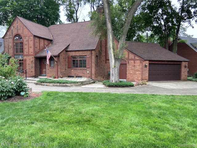 27943 Sunset Blvd W, Lathrup Village, MI 48076 - tudor house featuring brick siding, a front yard, driveway, a shingled roof, and an attached garage