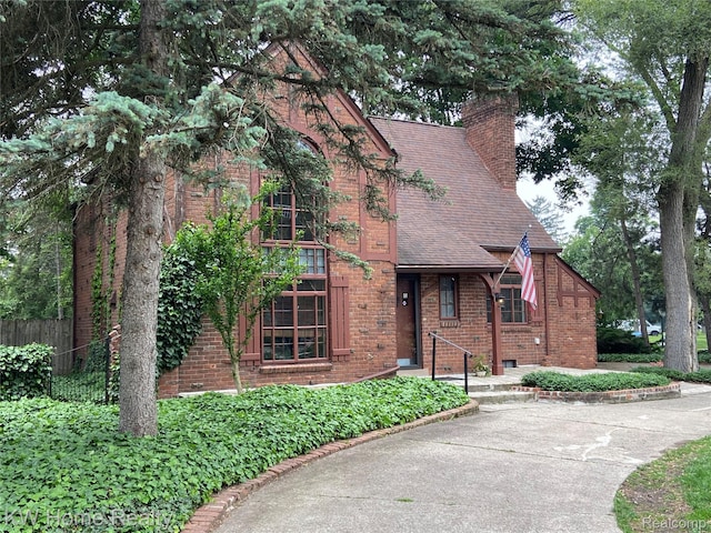 27943 Sunset Blvd W, Lathrup Village, MI 48076 - view of front of house with brick siding, a chimney, and roof with shingles