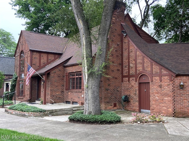 27943 Sunset Blvd W, Lathrup Village, MI 48076 - tudor-style house with roof with shingles, brick siding, and a chimney