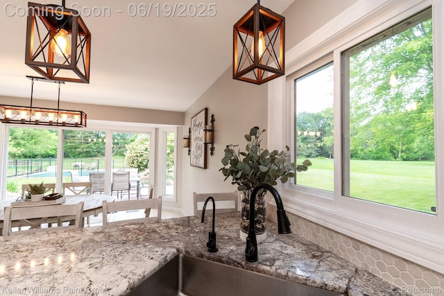 75757 Peters Dr, Bruce, MI 48065 - kitchen featuring stone countertops, vaulted ceiling, and hanging light fixtures