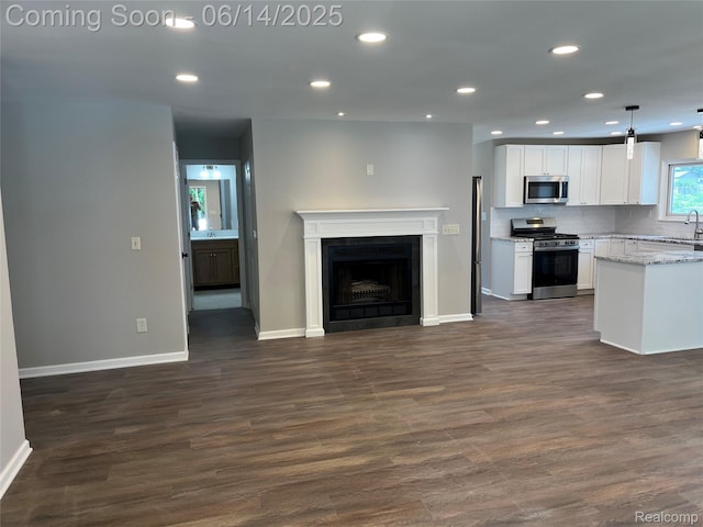 2145 Terrapin St, Wolverine Lake, MI 48390 - kitchen with stainless steel appliances, open floor plan, dark wood finished floors, white cabinetry, and backsplash