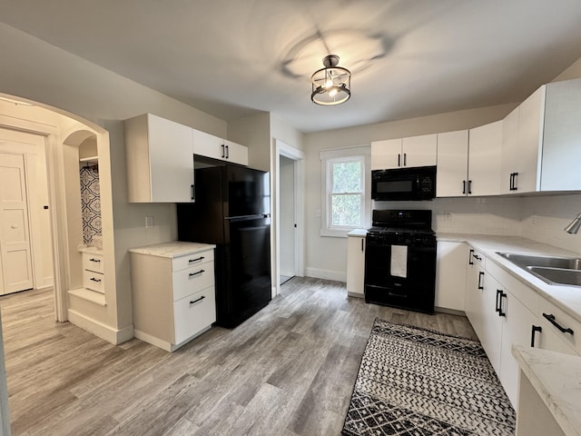 145 Sycamore St, Jackson, MI 49202 - kitchen with black appliances, light countertops, arched walkways, and light wood finished floors