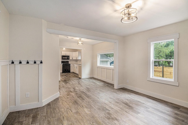 145 Sycamore St, Jackson, MI 49202 - unfurnished room with light wood-type flooring, plenty of natural light, and a chandelier