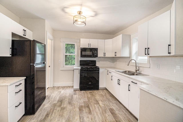 145 Sycamore St, Jackson, MI 49202 - kitchen with black appliances, tasteful backsplash, light wood-type flooring, and white cabinetry