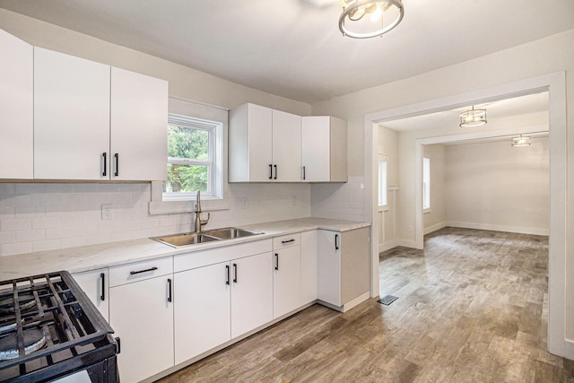 145 Sycamore St, Jackson, MI 49202 - kitchen featuring range, light countertops, light wood-style flooring, backsplash, and white cabinets