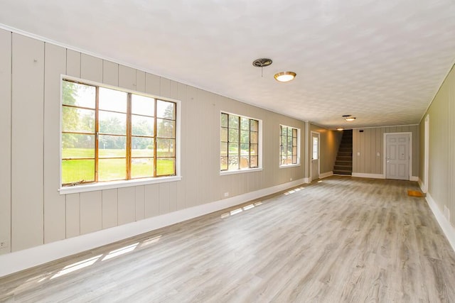 6604 E H Ave, Kalamazoo, MI 49048 - empty room featuring stairs, light wood finished floors, baseboards, and a decorative wall