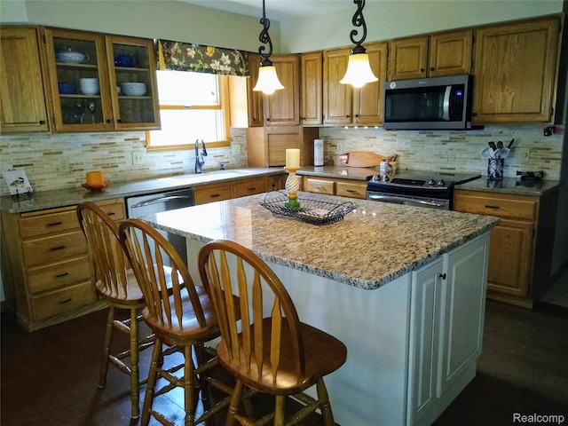 1455 Sand Rd, Port Austin, MI 48467 - kitchen with stainless steel microwave, black electric range, a kitchen island, a breakfast bar, and brown cabinets