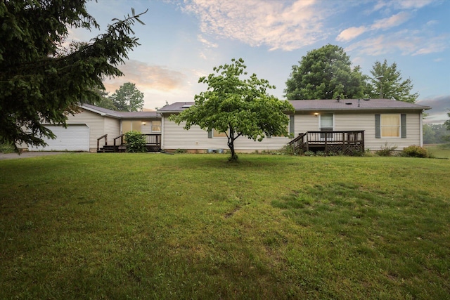 7100 Tripp Rd, Horton, MI 49246 - back of property at dusk featuring a wooden deck, a lawn, and an attached garage