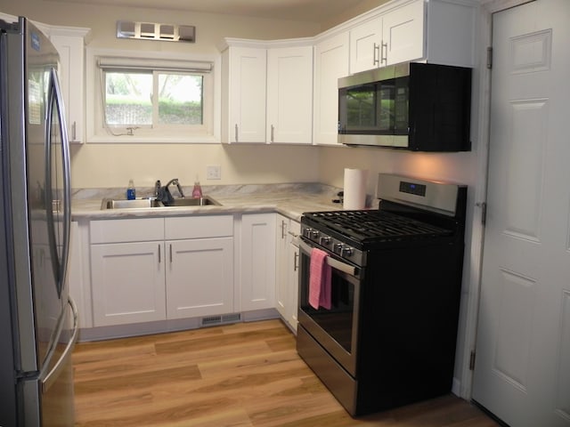 1097 Oliverda Rd, Sherwood, MI 49089 - kitchen featuring appliances with stainless steel finishes, a sink, light countertops, white cabinets, and light wood-style flooring