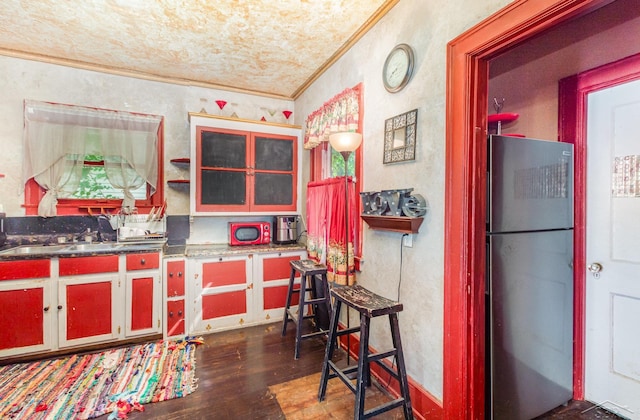234 N Jackson St, Bay City, MI 48708 - kitchen featuring freestanding refrigerator, ornamental molding, dark wood-style flooring, a sink, and a textured wall
