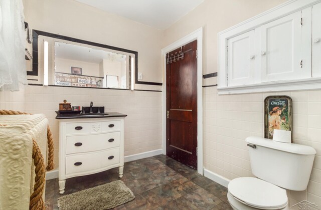 234 N Jackson St, Bay City, MI 48708 - bathroom with tile walls, toilet, vanity, stone finish floors, and baseboards