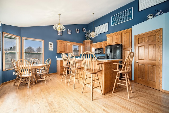 53029 Meadow View Ln, Paw Paw, MI 49079 - kitchen with black appliances, a breakfast bar area, light wood-type flooring, and high vaulted ceiling