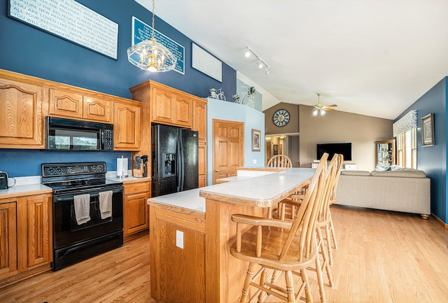 53029 Meadow View Ln, Paw Paw, MI 49079 - kitchen featuring black appliances, a kitchen breakfast bar, light countertops, light wood-style floors, and high vaulted ceiling