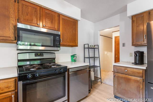 1710 Dykhouse Ave, Grand Haven, MI 49417 - kitchen featuring stainless steel appliances, light wood-style flooring, light countertops, and brown cabinetry